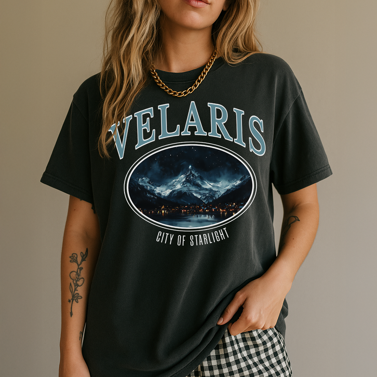 Person wearing a black t-shirt with 'VELARIS' and a mountain graphic design.