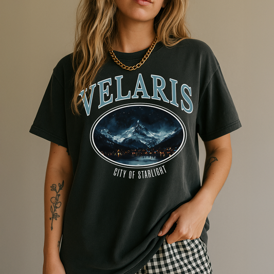 Person wearing a black t-shirt with 'VELARIS' and a mountain graphic design.