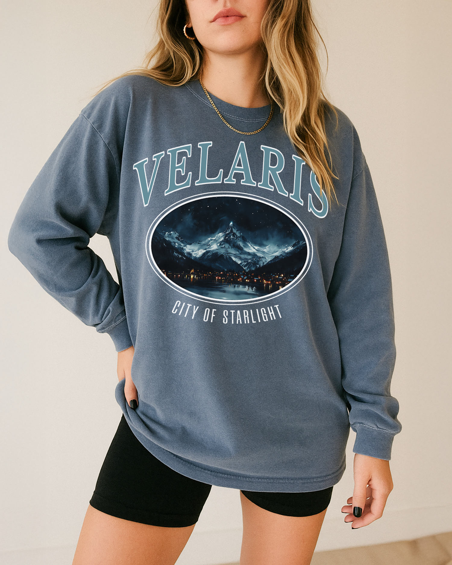Person wearing a blue sweatshirt with 'VELARIS' and mountain graphic design.